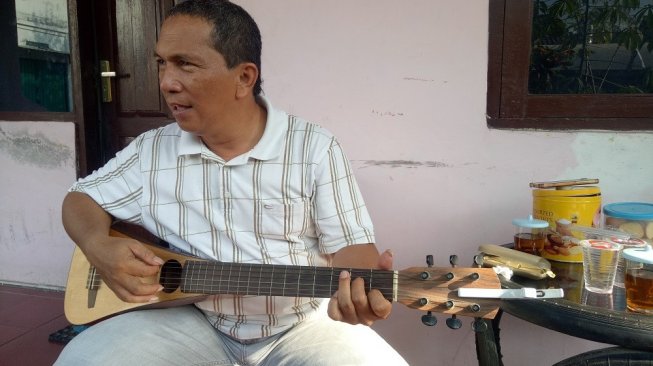 Johnsony Marhasak Lumbantobing dan gitar kesayangannya. [Suara.com/Eleonora Ata]