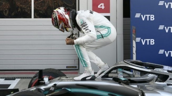 Pebalap Mercedes Lewis Hamilton berada di atas mobilnya merayakan suksesnya menjuarai F1 GP Rusia di Sochi Autodrom Circuit. Dimitar DILKOFF / AFP