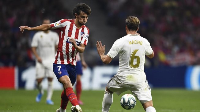 Pemain depan Atletico Madrid Joao Felix mencoba melewati bek Real Madrid Nacho Fernandez selama pertandingan sepak bola liga Spanyol antara Atletico Madrid melawan Real Madrid di stadion Wanda Metropolitano, Madrid, Spanyol, Minggu (29/9) dini hari WIB. [OSCAR DEL POZO / AFP]