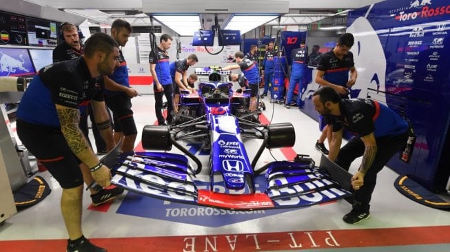 Kru tim Toro Rosso tengah menyiapkan mobil pebalap Pierre Gasly pada latihan bebas kedua F1 GP Singapura di Sirkuit Jalan Raya Marina Bay, Jumat (20/9/2019). [AFP/Mladen Antonov]