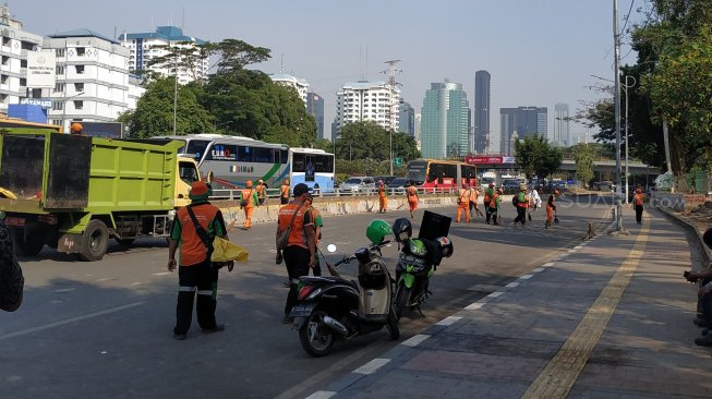 Petugas kebersihan dari Suku Dinas (Sudin) Lingkungan Hidup (LH) Jakarta Pusat langsung membersihkan sampah sisa aksi buruh di depan restoran pulau dua,  dekat gedung DPR RI, Senayan, Jakarta, Selasa (2/10/2019) siang. (Suara.com/Fakhri Fuadi)