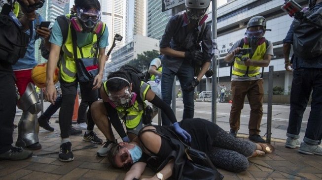 Seorang perempuan tergeletak terkena gas air mata yang dilontarkan polisi saat membubarkan aksi protes di Hong Kong. (AFP)