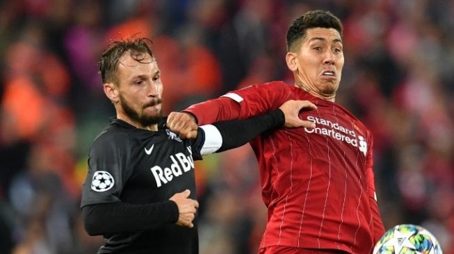 Penyerang Liverpool, Roberto Firmino (kanan) berebut bola dengan pemain FC Salzburg dalam lanjutan Liga Champions 2019/20 di Stadion Anfield, Kamis (3/10/2019). (Paul ELLIS / AFP)