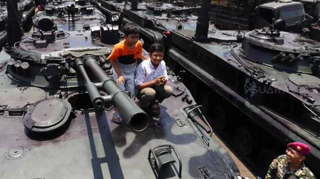 Sejumlah warga menaiki tank milik TNI yang terparkir di Landasan Udara Halim Perdanakusuma, Jakarta Timur, Sabtu (5/10). [Suara.com/Angga Budhiyanto]