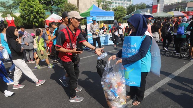 Relawan Komunitas Clean The City mengumpulkan sampah saat Car Free Day di Bundaran HI, Jakarta, Minggu (6/10). [Suara.com/Arya Manggala]