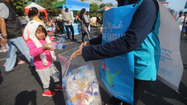 Relawan Komunitas Clean The City mengumpulkan sampah saat Car Free Day di Bundaran HI, Jakarta, Minggu (6/10). [Suara.com/Arya Manggala]