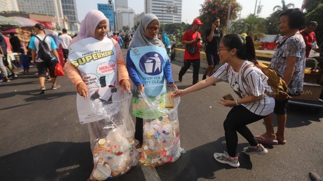 Relawan Komunitas Clean The City mengumpulkan sampah saat Car Free Day di Bundaran HI, Jakarta, Minggu (6/10). [Suara.com/Arya Manggala]