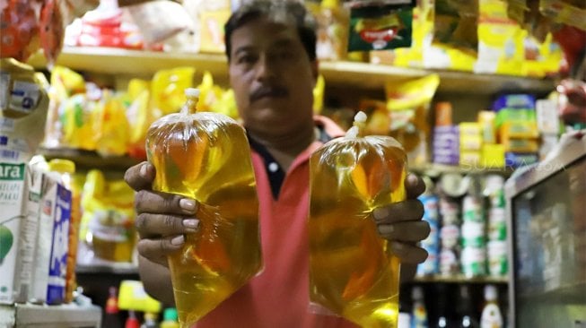 Pedagang menunjukkan minyak goreng curah di Pasar Santa, Jakarta, Selasa (8/10). [Suara.com/Angga Budhiyanto]