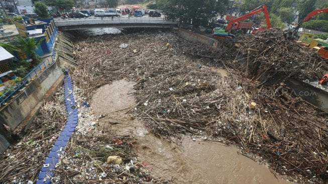 Pekerja dengan alat berat mengangkut sampah yang menumpuk di Pintu Air Manggarai, Jakarta, Rabu (9/10). [Suara.com/Arya Manggala]