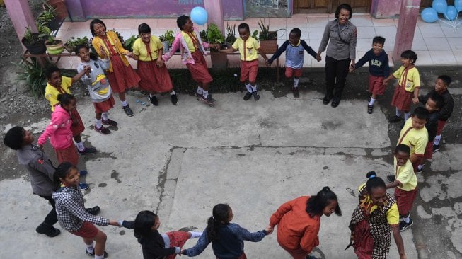 Seorang anggota Polisi wanita bermain dengan siswa SD Triesa Unggul Terpadu di Kota Wamena, Kabupaten Jayawijaya, Papua, Rabu (9/10). [ANTARA FOTO/M Risyal Hidayat]