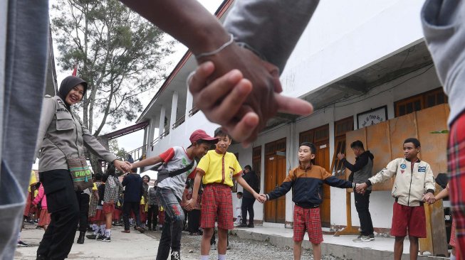 Seorang anggota Polisi wanita bermain dengan siswa SD Triesa Unggul Terpadu di Kota Wamena, Kabupaten Jayawijaya, Papua, Rabu (9/10/2019). [ANTARA FOTO/M Risyal Hidayat]