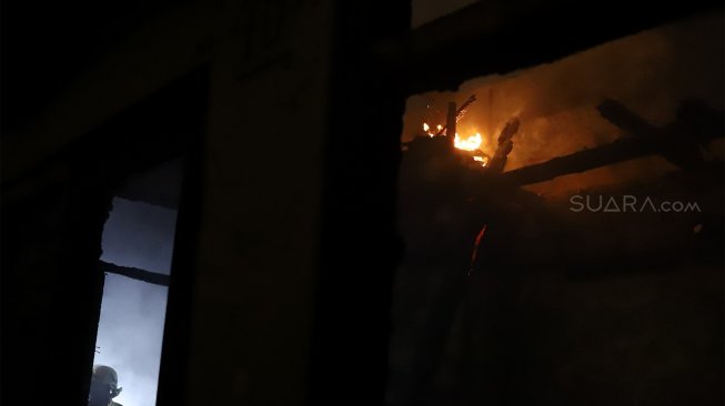 Petugas pemadam kebakaran berusaha memadamkan api yang menghanguskan rumah di kawasan Cawang Atas, Jakarta Timur, Rabu (9/10). [Suara.com/Angga Budhiyanto]