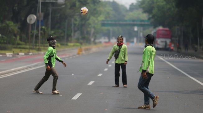 Sejumlah petugas Dinas Kehutanan Provinsi DKI Jakarta bermain sepak bola di tengah Jalan Medan Merdeka Barat yang ditutup, Jakarta, Kamis (10/9). [Suara.com/Arya Manggala]