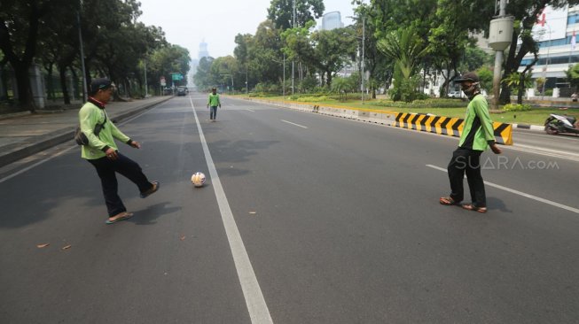 Sejumlah petugas Dinas Kehutanan Provinsi DKI Jakarta bermain sepak bola di tengah Jalan Medan Merdeka Barat yang ditutup, Jakarta, Kamis (10/9). [Suara.com/Arya Manggala]