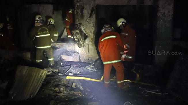 Petugas pemadam kebakaran berusaha memadamkan api yang menghanguskan rumah di kawasan Cawang Atas, Jakarta Timur, Rabu (9/10). [Suara.com/Angga Budhiyanto]
