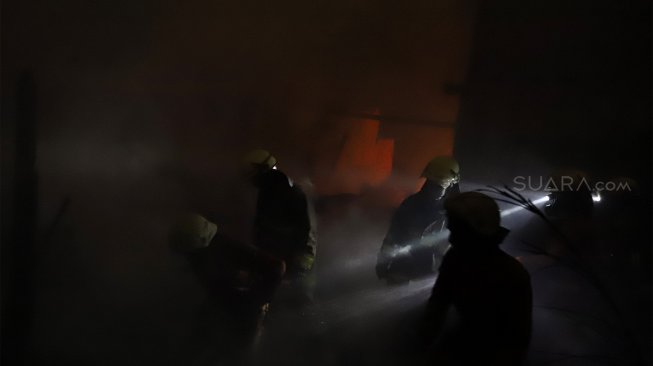 Petugas pemadam kebakaran berusaha memadamkan api yang menghanguskan rumah di kawasan Cawang Atas, Jakarta Timur, Rabu (9/10). [Suara.com/Angga Budhiyanto]