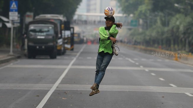 Sejumlah petugas Dinas Kehutanan Provinsi DKI Jakarta bermain sepak bola di tengah Jalan Medan Merdeka Barat yang ditutup, Jakarta, Kamis (10/9). [Suara.com/Arya Manggala]