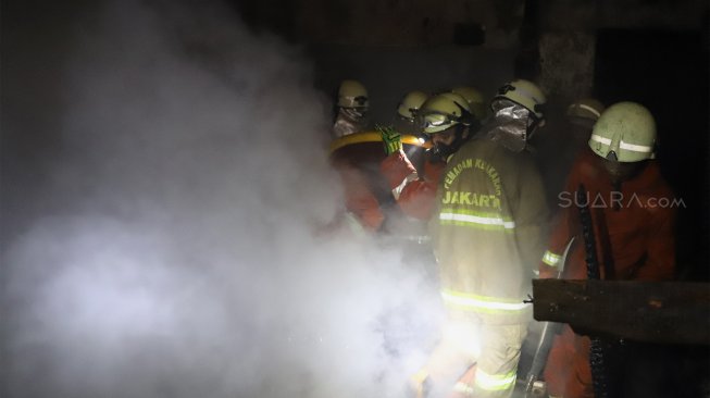 Petugas pemadam kebakaran berusaha memadamkan api yang menghanguskan rumah di kawasan Cawang Atas, Jakarta Timur, Rabu (9/10). [Suara.com/Angga Budhiyanto]
