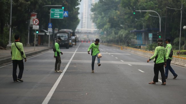 Sejumlah petugas Dinas Kehutanan Provinsi DKI Jakarta bermain sepak bola di tengah Jalan Medan Merdeka Barat yang ditutup, Jakarta, Kamis (10/9). [Suara.com/Arya Manggala]