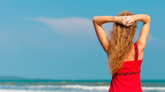 Perempuan berbaju merah di pinggir pantai. (Shutterstock)