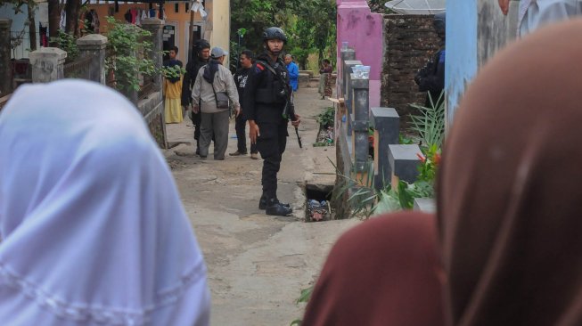 Polisi bersenjata lengkap berjaga di depan rumah kontrakan Syahril tersangka penusukan Menkopolhukam Wiranto di Kampung Sawah, Desa Menes, Pandeglang, Banten, Kamis (10/10). [ANTARA FOTO/Muhammad Bagus Khoirunas]