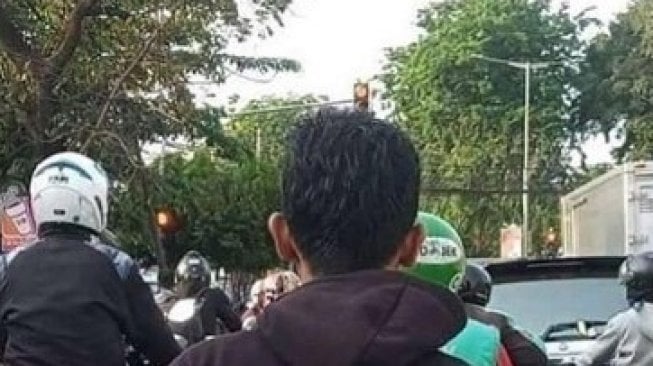 Pria Naik Motor Tak Pakai Helm, Warganet Pertanyakan Tulisan Jaketnya