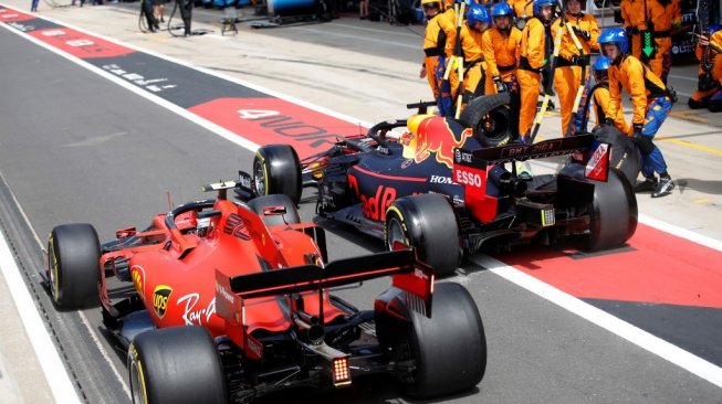 Pebalap Ferrari, Charle Leclerc (kiri), nyaris bertabarkan dengan driver Red Bull, Max Verstappen, di pit lane dalam balapan F1 GP Inggris di Sirkuit Silverstone, Minggu (14/7/2019). [AFP/Matthew Childs]