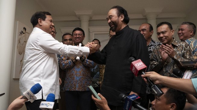 Ketua Umum Partai Gerindra Prabowo Subianto (kiri) berjabat tangan dengan Ketua Umum Partai NasDem Surya Paloh (tengah) usai melakukan pertemuan di kawasan Permata Hijau, Jakarta, Minggu (13/10). [ANTARA FOTO/Dhemas Reviyanto]