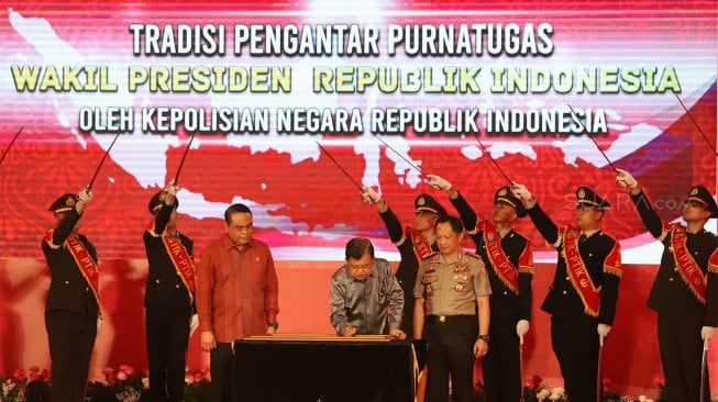 Wakil Presiden Republik Indonesia, Drs. H. Muhammad Jusuf Kalla menuliskan kesan dan pesan saat Tradisi Pengantar Purna Tugas Wakil Presiden di STIK-PTIK, Jakarta Selatan, Jumat (18/10). (Suara.com/Angga Budhiyanto)
