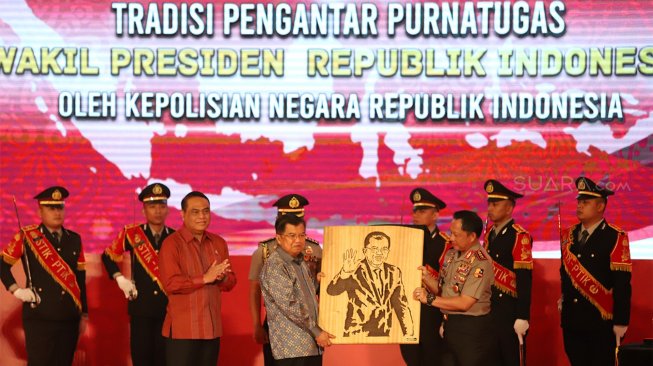 Wakil Presiden Republik Indonesia, Drs. H. Muhammad Jusuf Kalla menerima cenderamata berupa lukisan saat Tradisi Pengantar Purna Tugas Wakil Presiden di STIK-PTIK, Jakarta Selatan, Jumat (18/10). (Suara.com/Angga Budhiyanto)
