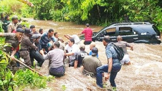 Saat Bupati Kepulauan Yapen Toni Tesar dan istri berhasil selamat keluar dari mobil yang dibantu Satpol PP dan warga setempat. (KabarPapua.co/IST)