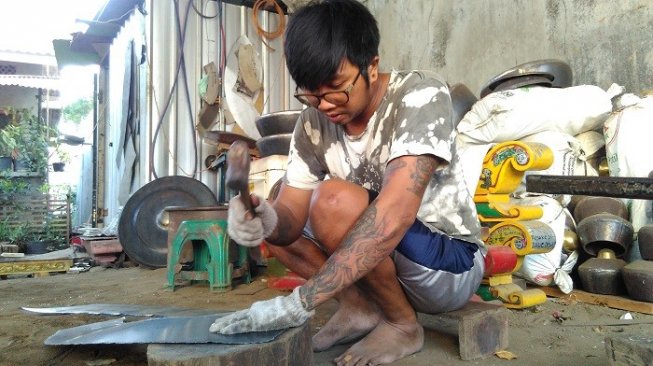 Seorang pekerja sedang membuat gong, di rumah produksi gamelan Bondho Gongso, Gamping, Sleman, Yogyakarta. (Suara.com/Uli Febriarni)