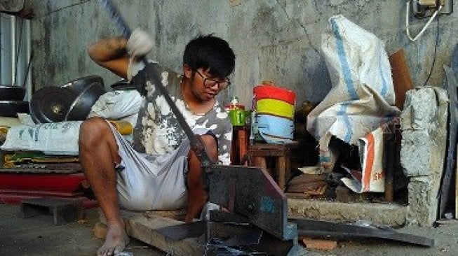 Seorang perajin rumah gamelan Bondho Gongso tengah mengerjakan instrumen musik tradisional Jawa itu [Suara.com/Uli Febriarni].