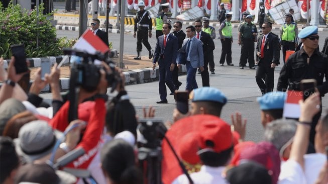 Presiden Joko Widodo menyapa para pendukungnya di Jalan Merdeka Barat, Jakarta, Minggu (20/10). [Suara.com/Angga Budhiyanto]