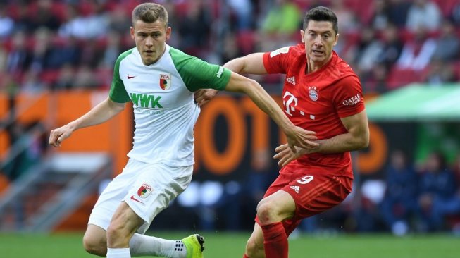 Penyerang Bayern Munich, Robert Lewandowski (kanan) berduel dengan penyerang Augsburg, Alfred Finnbogason pada lanjutan Bundesliga 2019/20, Sabtu (19/10/2019). [Christof STACHE / AFP]