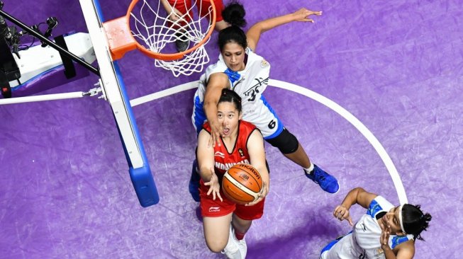 Atlet cantik Timnas basket putri Indonesia, Priscilla Annabel Karen (tengah), melakukan layup yang coba dihadang dua pemain India dalam laga penyisihan grup Asian Games 2018 di Jakarta, Kamis (23/8). [AFP/Anthony Wallace]