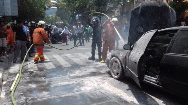 Petugas pemadam kebakaran saat memadamkan api di mobil Honda Accord yang terbakar. (Dok. pemadam kebakaran).