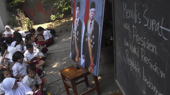 Siswa SD Negeri Madyotaman Solo menulis surat untuk Presiden Joko Widodo dan dan Wakil Presiden Ma'ruf Amin di sekolah setempat, Solo, Jawa Tengah, Selasa (22/10).  [ANTARA FOTO/Maulana Surya]