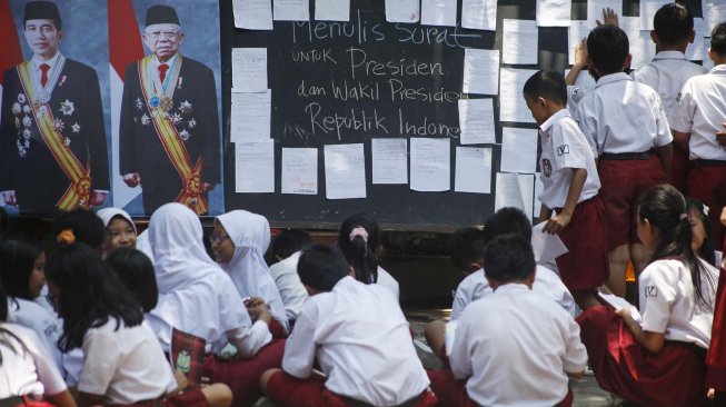 Siswa SD Negeri Madyotaman Solo menulis surat untuk Presiden Joko Widodo dan dan Wakil Presiden Ma'ruf Amin di sekolah setempat, Solo, Jawa Tengah, Selasa (22/10).  [ANTARA FOTO/Maulana Surya]