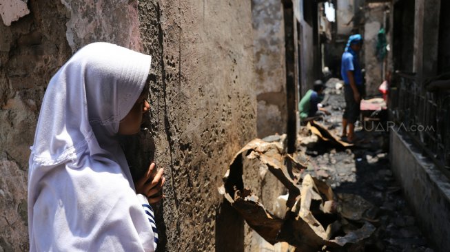 Warga berada di antara puing sisa kebakaran di Jalan Setia, Bidara Cina, Jatinegara, Jakarta, Selasa (22/10). [Suara.com/Arya Manggala]