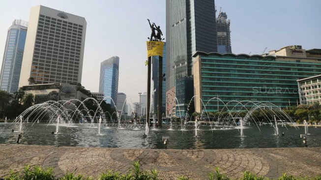 Aktivis Greenpeace membentangkan spanduk di Patung Selamat Datang, di Bundaran HI, Jakarta, Rabu (23/10).[Suara.com/Arya Manggala]