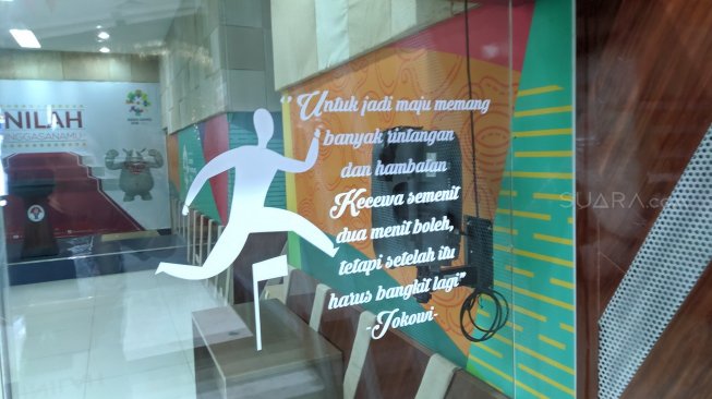 Stiker pernyataan Presiden Joko Widodo (Jokowi) yang menempel di sebelah kanan pintu Media Center Kemenpora Senayan, Jakarta, Rabu (23/10/2019). [Suara.com/Arief Apriadi]