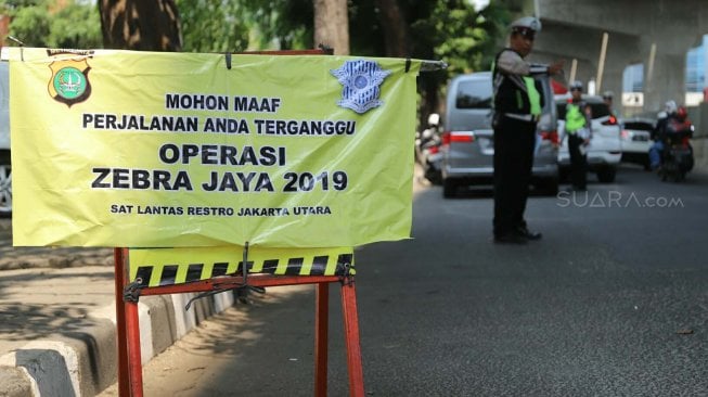 Petugas kepolisian memeriksa kelengkapan surat kendaraan bermotor saat Operasi Zebra Jaya 2019 di Jalan Boulevard, Jakarta, Kamis (24/10). [Suara.com/Arya Manggala]