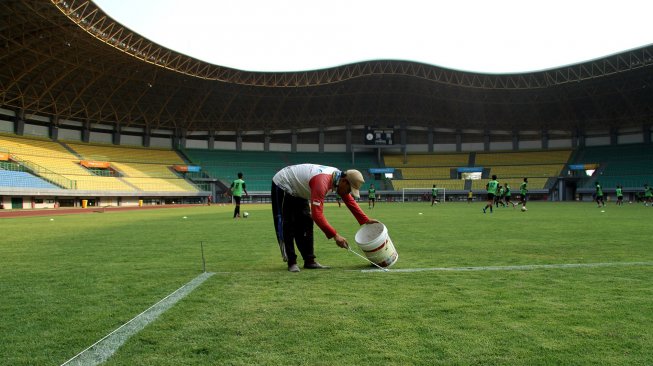 Pekerja melakukan perawatan rumput lapangan Stadion Patriot Candrabhaga, di Bekasi, Jawa Barat, Jumat (25/10). [ANTARA FOTO/Risky Andrianto]