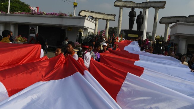 Sejumlah pelajar membentangkan bendera Merah Putih saat digelar Upacara Sumpah Merah Putih dalam rangka peringatan Hari Sumpah Pemuda di lapangan Tugu Pahlawan, Surabaya, Jawa Timur, Sabtu (26/10). [ANTARA FOTO/Zabur Karuru]