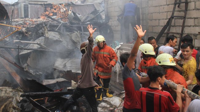 Petugas Pemadam Kebakaran memadamkan rumah yang terbakar di Jalan Anyer, Jakarta, Sabtu (26/10). [Suara.com/Oke Atmaja]