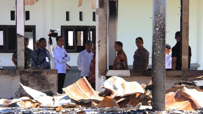 Presiden Joko Widodo mengamati bangunan yang terbakar saat kerusuhan lalu di Kantor Bupati Jayawijaya, Wamena, Papua, Senin (28/10).  [ANTARA FOTO/Anyong]