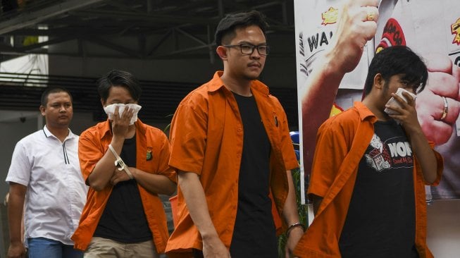 Petugas menggiring tersangka pengedar cairan rokok elektrik yang mengandung tembakau gorilla saat rilis di Mapolda Metro Jaya, Jakarta, Senin (28/10). [ANTARA FOTO/Nova Wahyudi]