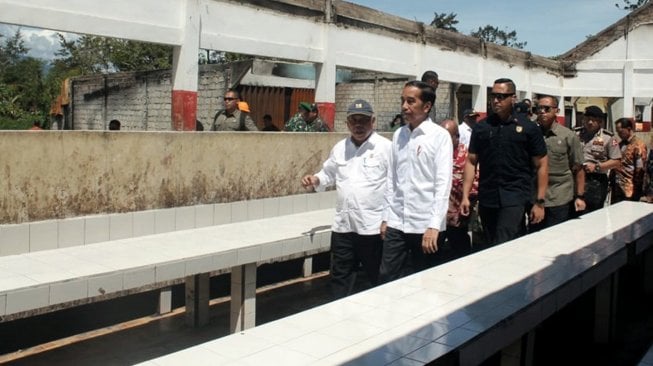 Presiden Joko Widodo mengamati bangunan yang terbakar saat kerusuhan lalu di Kantor Bupati Jayawijaya, Wamena, Papua, Senin (28/10).  [ANTARA FOTO/Anyong]