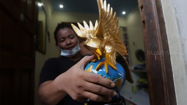 Pekerja menyelesaikan pembuatan plakat wayang dan garuda di Industri Rumahan Pluit, Penjaringan, Jakarta Utara, Rabu (30/10). [Suara.com/Angga Budhiyanto]
